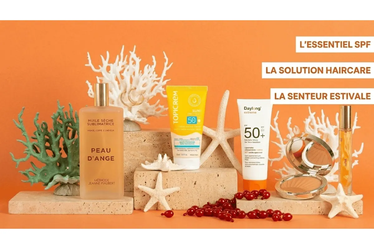 Box Marie Claire Beauté Solaire mise en avant des essentiels SPF haircare et senteur estivale huile Peau d'Ange Méthode Jeanne Piaubert crème Topicrem SPF50 lait Daylong SPF50 plus poudre bronzante Clarins eau de parfum Gas Bijoux corail blanc étoiles de mer fond orange