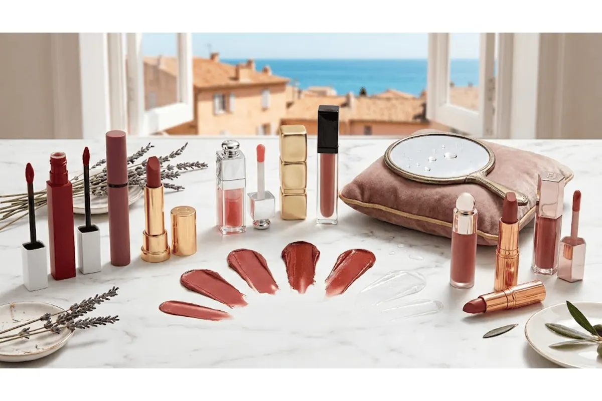 Sélection rouges à lèvres mat et brillants posés sur plan marbre vue mer méditerranée, swatchs nude rouge, miroir doré, lavande