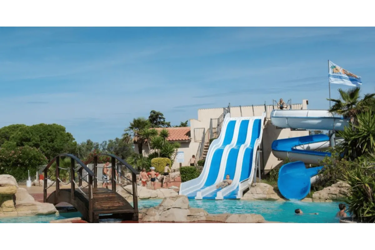 Parc aquatique avec toboggans bleus et palmiers dans l'Hérault, ambiance vacances et loisirs nautiques pour le concours Hérault Tourisme