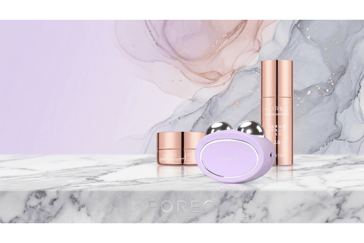 Foreo Bear violet lavande avec sérum Supercharged et crème rose gold sur marbre blanc fond aquarelle mauve